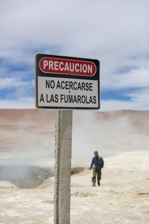 Silhouette of man walking behind a danger stop warning sign post in Solar de Manana geyser, Boliviaの写真素材