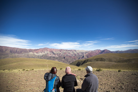 HUMAHUACA, ARGENTINA, DEC 21: Three undefined tourists sitting in front of the mountain of fourteen colors, Quebrada de Humahuaca against a blue sky, Northern Argentina 2014のeditorial素材