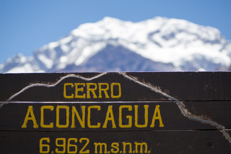 Welcome wooden sign at the Aconcagua National Park with the peak of the mountain at 6962 meters above sea level and a clear blue sky in the background, Andes Mountains, Argentinaのeditorial素材