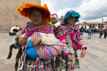 Peruvian Indian women in traditional clothes carrying babies and a baby sheep on the Plaza de Armas of Cusco. Peru 2015のeditorial素材
