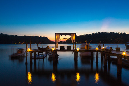 Romantic sunset with silhouette of lounges and pergola on wooden pier at sunset in Koh Chang. Perfect romantic tropical scene in Thailand. Long time exposure.の写真素材