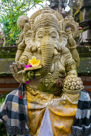 Traditional balinese offerings to gods with frangipani flowers and details of Ganesh sculpture. Bali Island in Indonesiaの写真素材