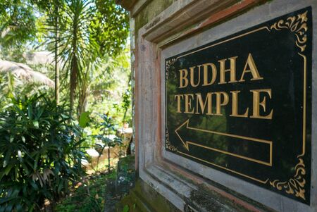 Sign giving the direction to the Buddha Balinese temple in the tropical jungle near Ubud in Bali Island, Indonesiaの写真素材