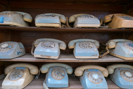 Rows of wooden shelves with old vintage used blue phones from the 1980s. Bali. Indonesiaの写真素材