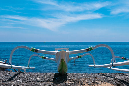 Side view of traditional Indonesian fisher standing on the beach beautiful boat at Amed Beach in...