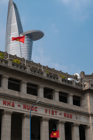 Communist flag waving in front of government office with the tallest building Bitexco Financial Tower contre a clear blue sky in Vietnam. 2016のeditorial素材