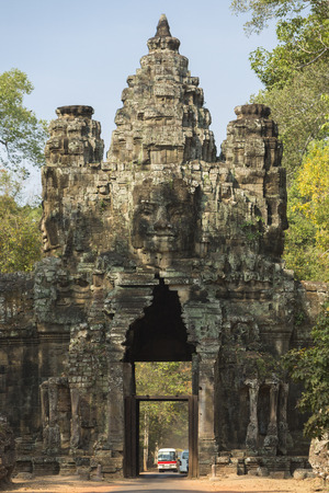 Details of stone Gate of Angkor Thom with small tourist bus in Cambodiaの写真素材