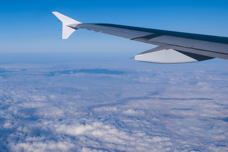 Aircraft wing flying over clouds with clear blue sky of Dubai in the background.の写真素材