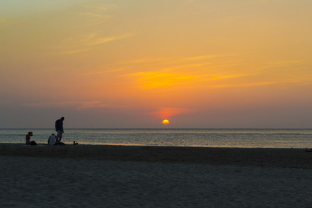 Silhouette of a couple watching a colorful sunset on a beach in Santa Marta, Colombiaの写真素材