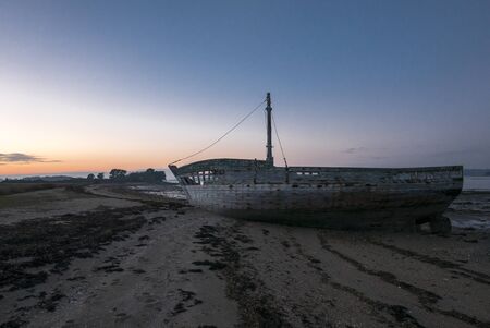 Beautiful sunset and wooden shipwreck standing on the beach taken from the Island of Arz in Brittany (Morbihan), France.の写真素材