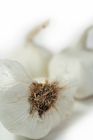 Half clove of garlic on white with whole cloves blurred in the backgroundの写真素材