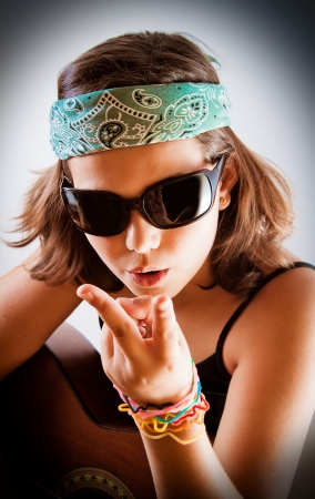 Pre-teen girl with acoustic guitar wearing sunglasses and bandanna and making peace  victory sign の写真素材