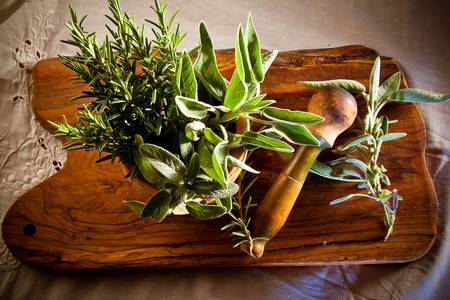 Old and weathered pestel and mortar on a wooden board, full of fresh rosemary and sage ready to be crushed  の写真素材