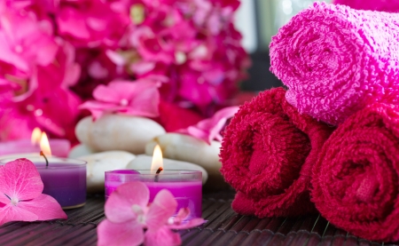 Close-up on rolled towels, with flowers and candles in the background. Spa scene, relaxation, pampering.の写真素材