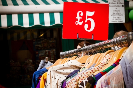 Bargain for a fiver: second-hand clothes for sale at market. Recession theme.