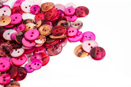 PInkand red mother-of-pearl buttons against a white background. Plenty of copy space.