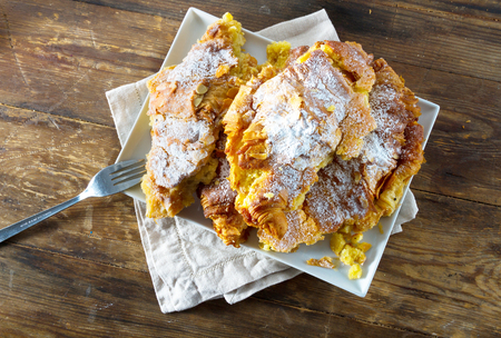 Continental breakfast: delicious almond croissants sprinkled with icing sugar and with a custard fillin, on a rustic wooden background.の写真素材