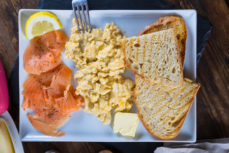 A plate with scrambled eggs with salmon and toasted bread. Delicious breakfast.の写真素材