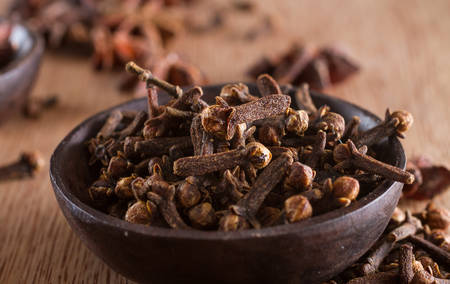 Spices series: closeup on a bowl full of cloves against a wooden background. Copy space.の写真素材