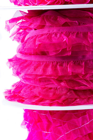 Stack of reels of ribbon in all shades of pink and red. On white background.の写真素材