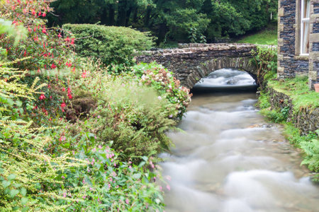 A beautiful waterfall by an old bridge in the Lake District, England. Misty weather.の写真素材