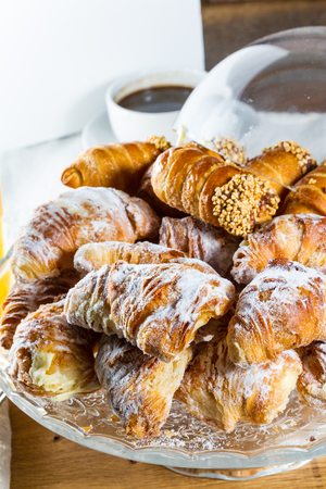Typical continental breakfast with sugar-coated cannoli and croissants filled with custard.の写真素材