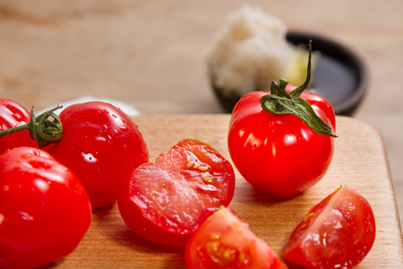 Ripe red cherry tomatoes on a wooden board, with rosemary focaccia and olive oil.の写真素材