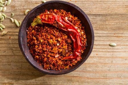 Wooden bowl full of fiery chilli pepper flakes.の写真素材