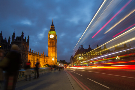 A bus speeding past tourists admiring Big ben and Houses of Parliamentの写真素材