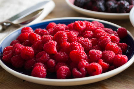 Blue plate full of juicy,delicious, healthy raspberries. Shallow depth of fieldの写真素材