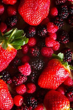 Fruits of the forest: strawberries, raspberries and blackberries against wooden background.. Healthy...