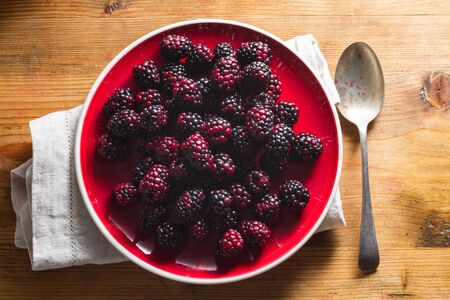 Fruits of the forest:  blackberries. Healthy breakfast food. On red plate against wooden bckground.の写真素材
