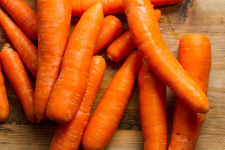 Raw carrots against a rustic wooden background.の写真素材