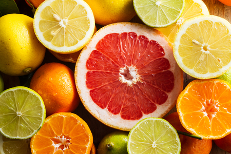 Juicy half pink grapefruit for a healthy breakfast. Limes, lemons, clementines around it.の写真素材