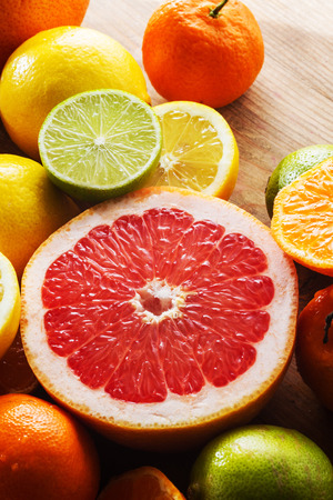Juicy half pink grapefruit for a healthy breakfast. Limes, lemons, clementines around it.の写真素材