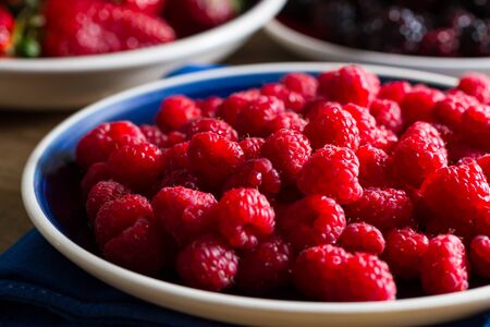 Fruits of the forest:  raspberries. Shallow depth of field. Strawberries and blackberries in the background.の写真素材