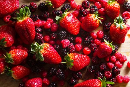 Fruits of the forest: strawberries, raspberries and blackberries against wooden background.. Healthy breakfast food.の写真素材