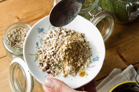 Middle Eastern cuisine: chef mixing spices and herbs to give flavour to the food. On the plate you can see sunflower seeds, powdered garlic and ginger.の写真素材