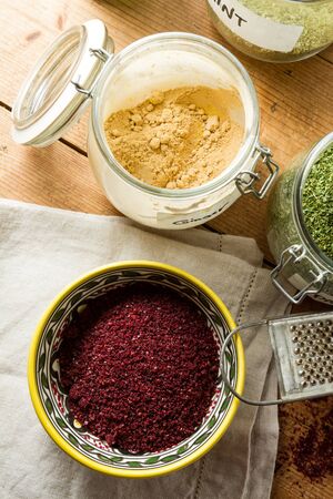 Middle Eastern cuisine: bowl of sumac, jar with dried ginger, mint and other herbs. Sumac powder is used in Arabic cuisine to add zest and flavour to dishes.の写真素材