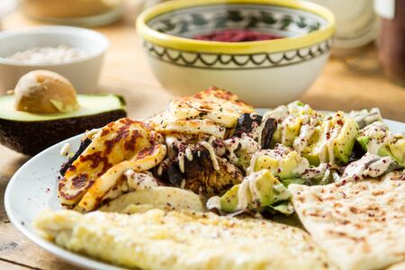 Middle Eastern cuisine: delicious plate of grilled halloumi cheese served with a lettuce and avocado salad, seasoned with sumac and other spices.の写真素材