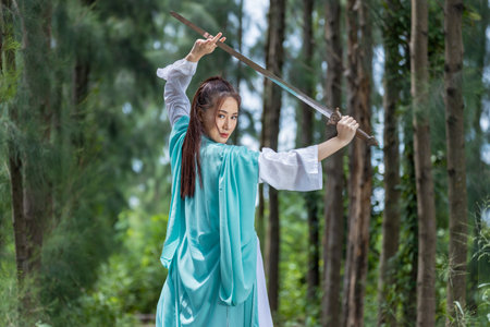 Young beautiful Asian woman dressed in ancient Chinese warrior style with ancient fan. cute girl in green dressの写真素材