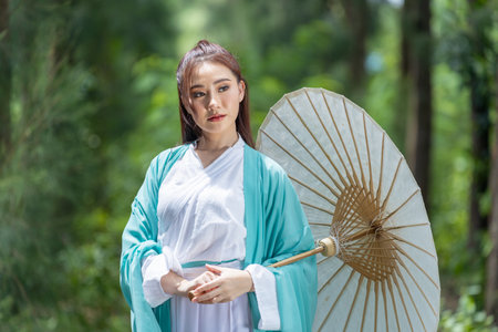 Young beautiful Asian woman dressed in ancient Chinese warrior style with ancient fan. cute girl in green dressの写真素材