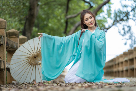 Young beautiful Asian woman dressed in ancient Chinese warrior style with ancient fan. cute girl in green dressの写真素材