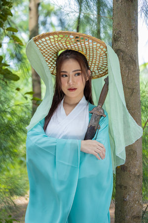 Young beautiful Asian woman dressed in ancient Chinese warrior style with ancient fan. cute girl in green dressの写真素材