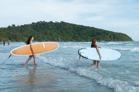 Two teenage girls in blue summer bikinis and his favorite surfboard.の写真素材