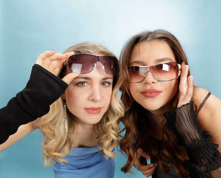 2 young hipster women look interested directly into the camera | close-up portrait, isolated against...