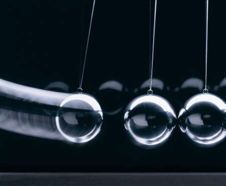 close-up of 3 balls of a newton pendulum in action against a dark backgroundの写真素材