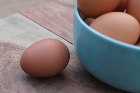 Close-up view of raw chicken eggs in blue bowlの写真素材