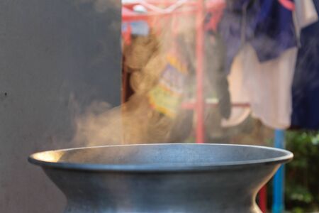 Traditional silver steamer pot with white smoke while cookingの写真素材