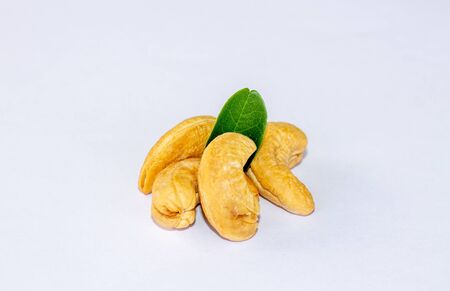 Raw cashew nuts with green leaves isolated on white background. Macro, studio shotの写真素材